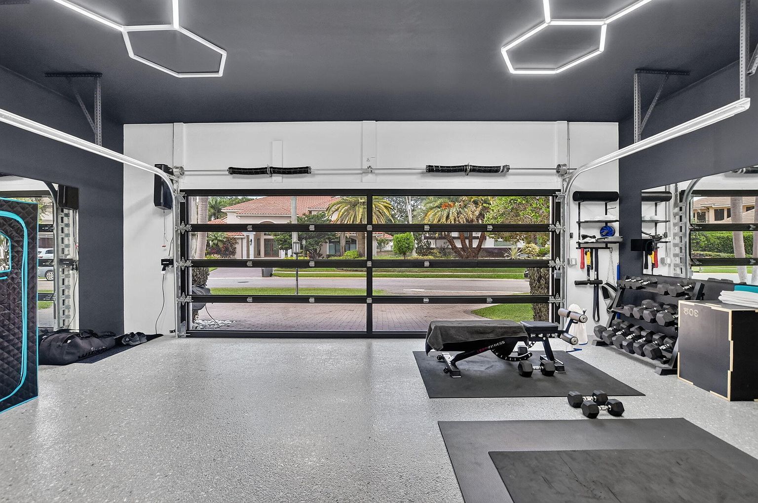 Garage gym with a glass garage door, hexagon LED lighting and full equipment