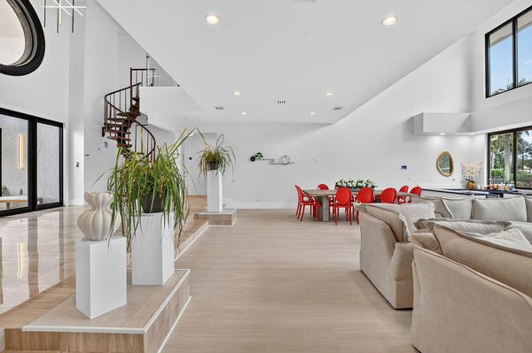 Open-concept living and dining area with the spiral staircase and red dining chairs beyond