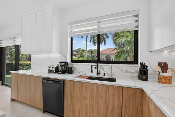 Kitchen sink wall with marble countertops and a window looking out on the palms