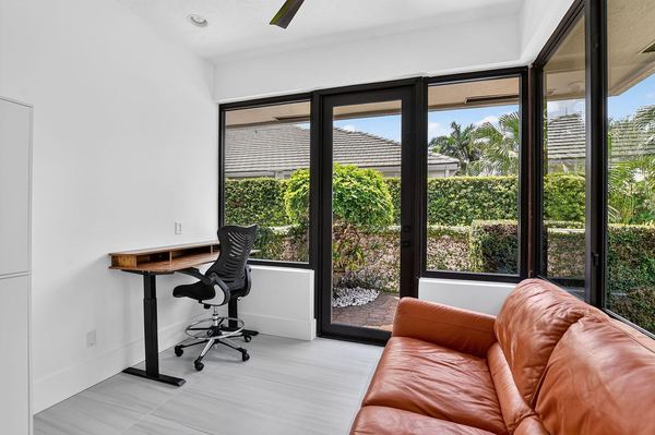 Office nook with a standing desk, a leather sofa and glass doors to the garden