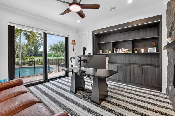 Study with dark built-in shelving and sliding doors to the pool