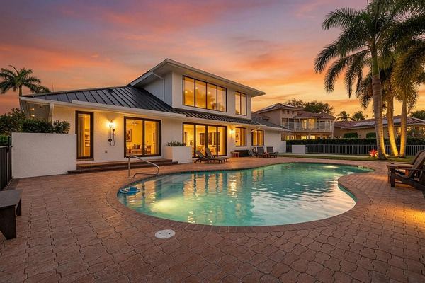 Rear of the home at twilight, with the lit pool and paver deck