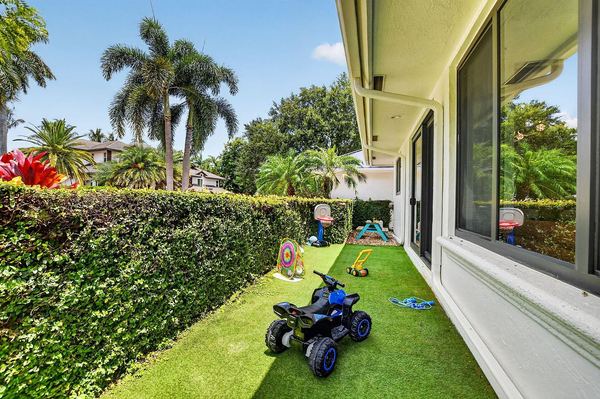 Private turf play area enclosed by hedges, with a ride-on toy